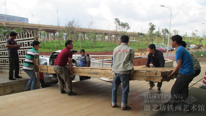 昆明長(zhǎng)水國(guó)際機(jī)場(chǎng)定制的辦公樓大廳大型紅木迎客松鐵畫屏風(fēng)-正在搬運(yùn)鐵畫屏風(fēng)包裝箱